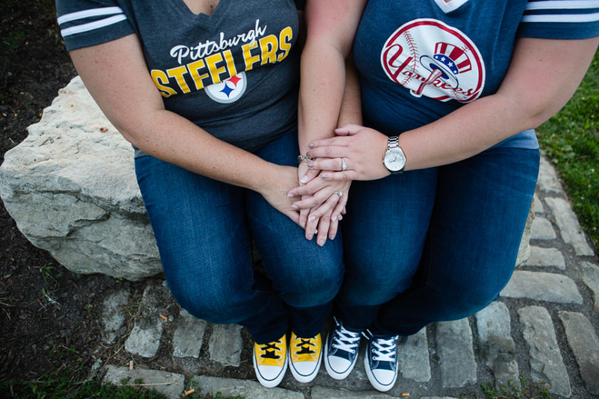Women in Pittsburgh Steelers and New York Yankees T Shirts sitting together holding hands