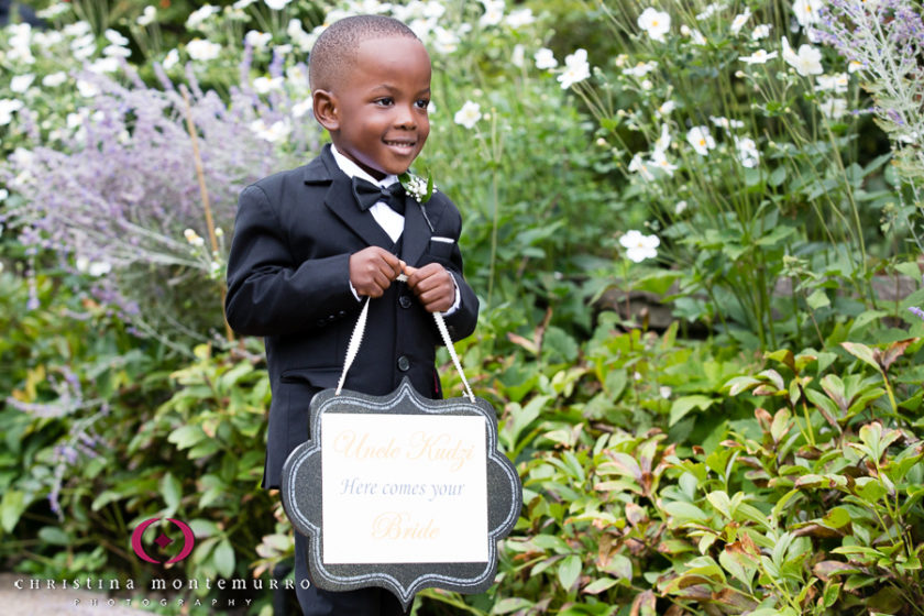 Adorable ring bearer carrying "here comes the bride" sign