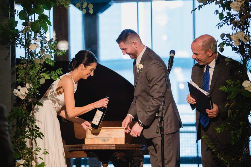 Bride and groom putting wine into wine box during their wedding ceremony