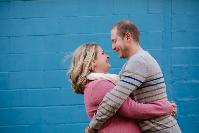Engaged Couple in front of Blue Wall in Pittsburgh's Strip District