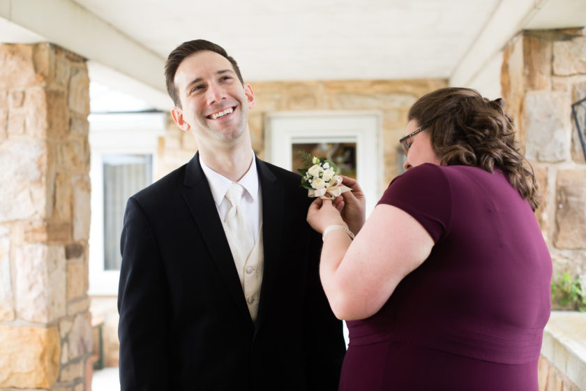 Maid of honor pinning boutonniere on groom