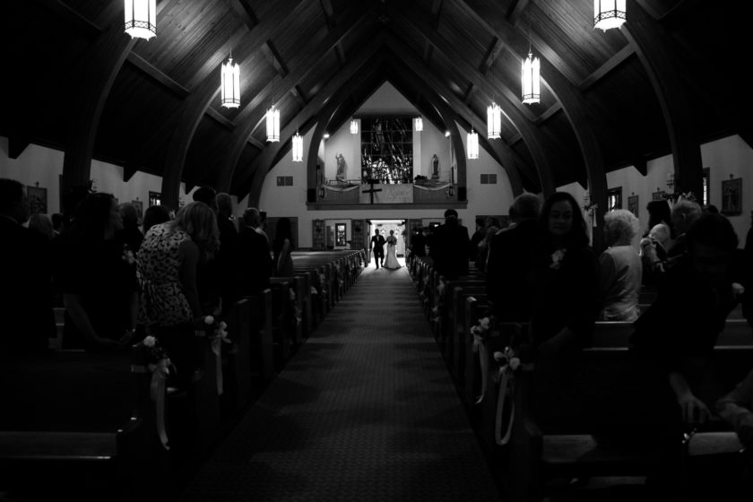 Silhouette of bride and her father walking into church ceremony